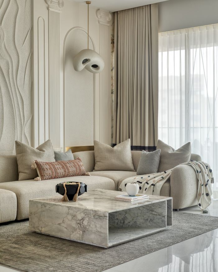 The focal wall, with its textured stucco artistry and fluted Greek-inspired pilasters, sets a sculptural tone, creating a sense of architectural nostalgia while feeling distinctly contemporary. The lights are customised, cushions by AA Living, carpets and rugs from Loop by LJ and curtains by Pride Furnishings;  Photography by Pulkit Sehgal