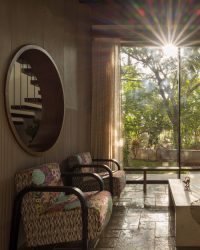 Light filters through trees into the lounge, casting patterns across exposed brick and textured walls; Styling by Fymin Naif and Nimitha Harith; Photography by Justin Sebastian
