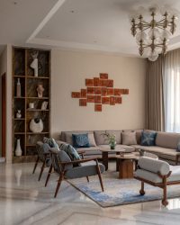 The living area is a lesson in Indo-Moroccan aesthetics, courtesy of design elements like a Moroccan-style glass chandelier, custom wood panelling with silk wood veneer bookshelves and 3D concrete panels with arched forms; Photography by Kuber Shah