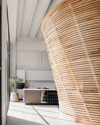 The monolithic, freestanding wooden space divider forms the centerpiece of the store's interiors. Paired with the vaulted ceiling, it imparts a distinctive character without the need for decorative accessories. The light oak finish set against the store’s white canvas creates sophistication; Photography by Ishita Sitwala